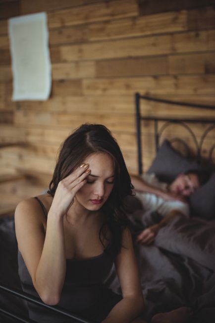 upset woman sitting at the edge of the bed